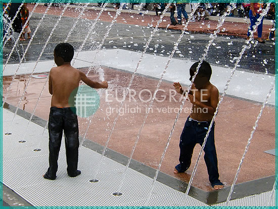 bambini che giocano con l'acqua in sicurezza su un pavimento in grigliato